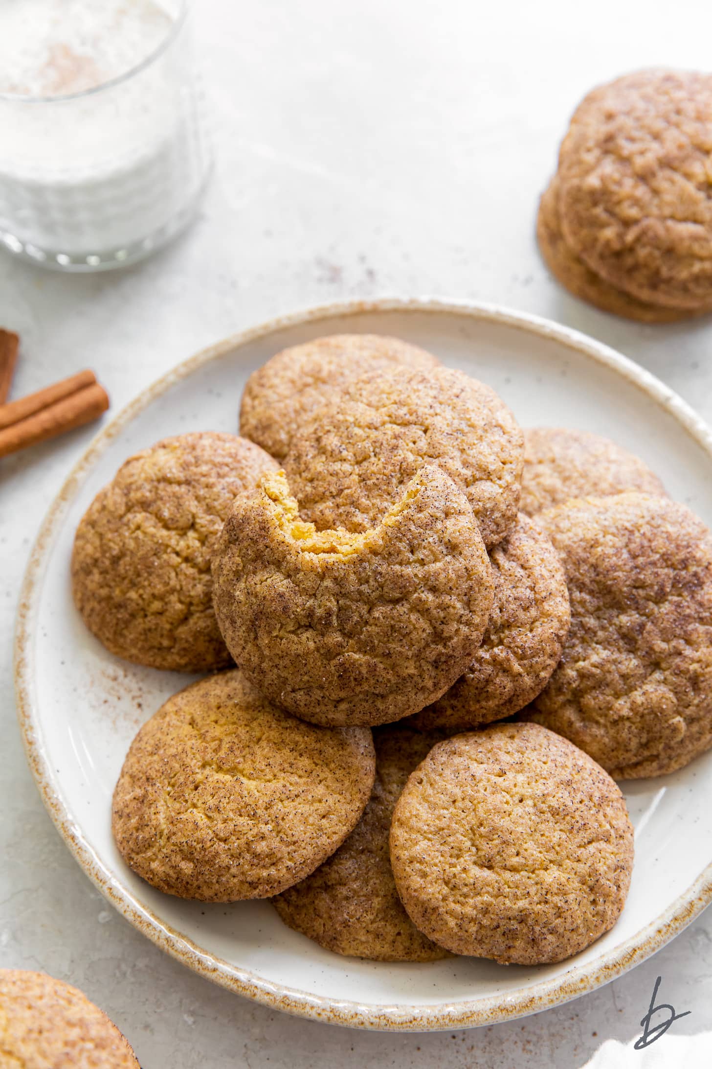 pumpkin snickerdoodles on white plate and top cookie with a bite