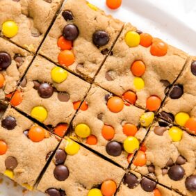 reeses pieces peanut butter blondies cut into squares on parchment paper