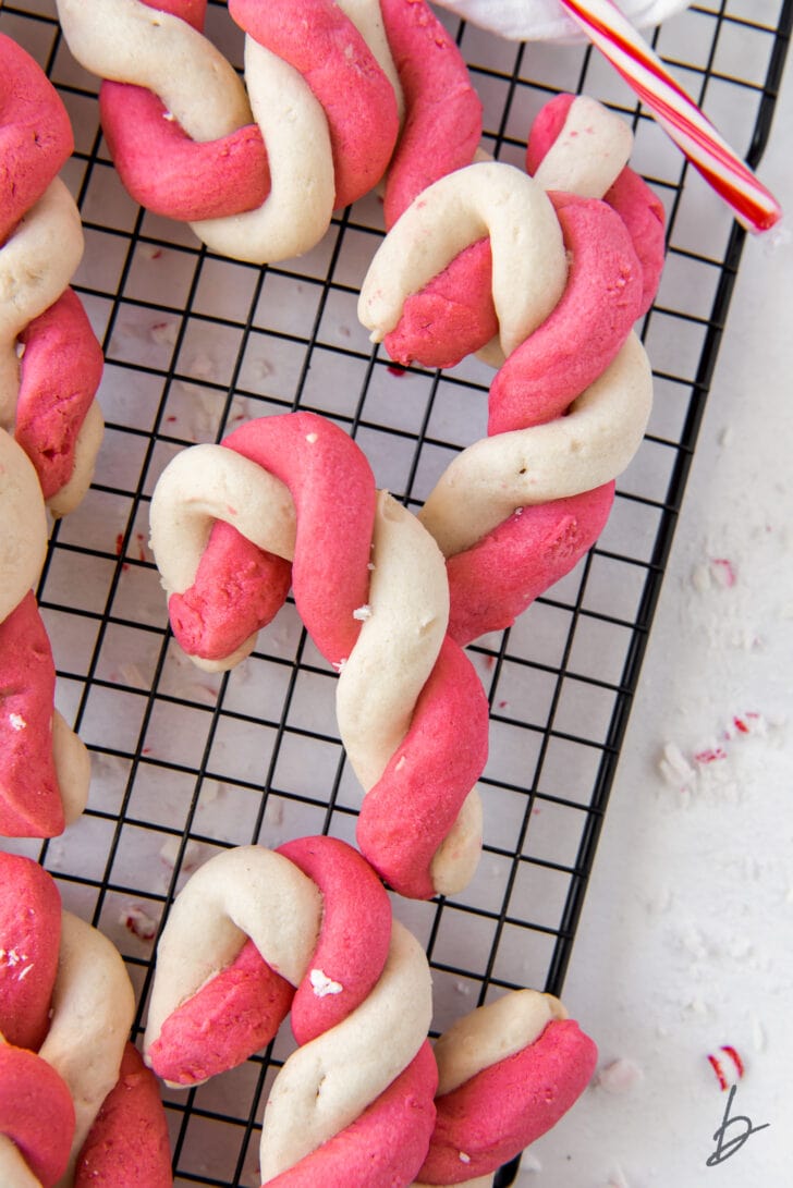 red and white twist candy cane cookies on black wire cooling rack