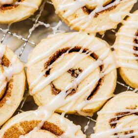 cinnamon roll cookies with icing on cooling rack