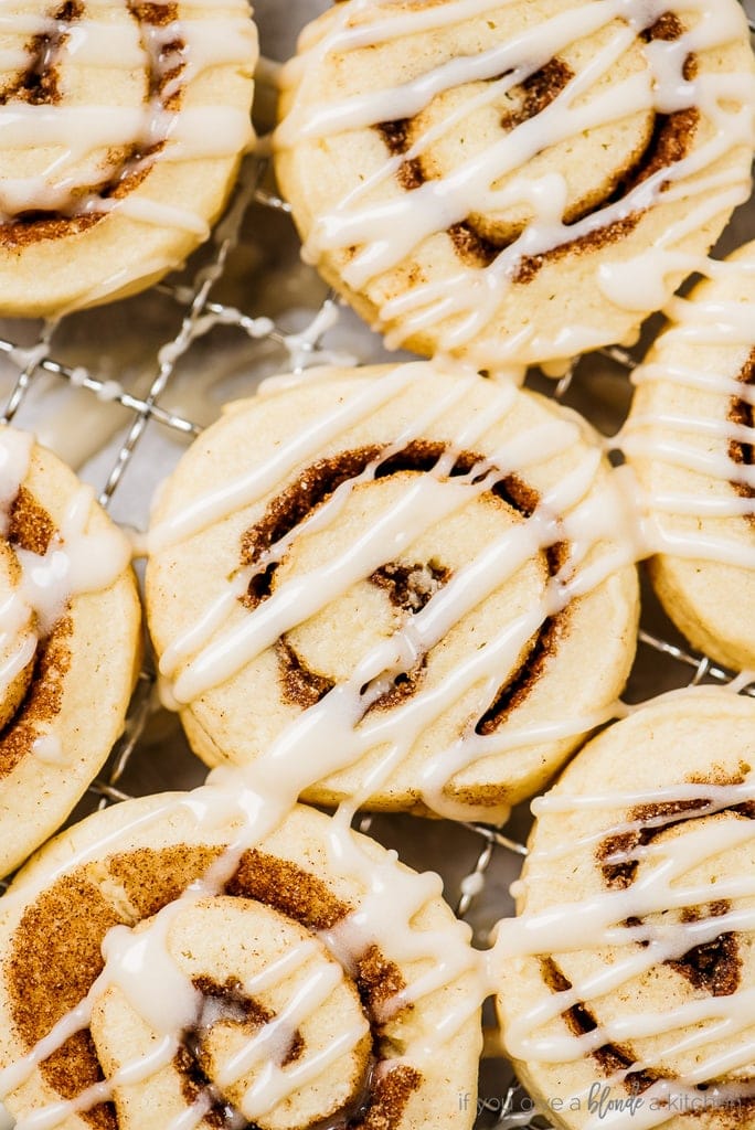cinnamon roll cookies with icing on cooling rack