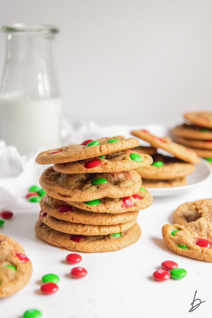 Christmas M&M cookies stacked with red and green M&M candies and glass milk bottle