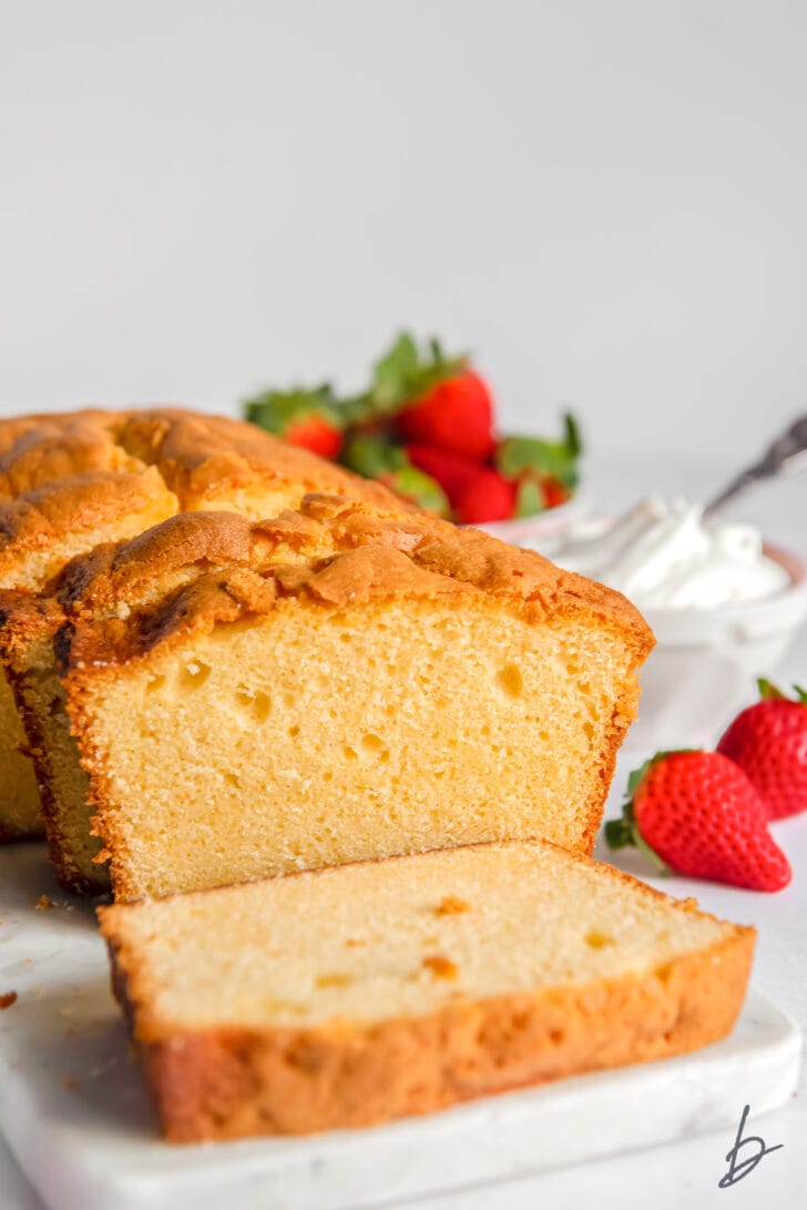 cream cheese pound cake loaf with slice cut off the end next to fresh strawberries