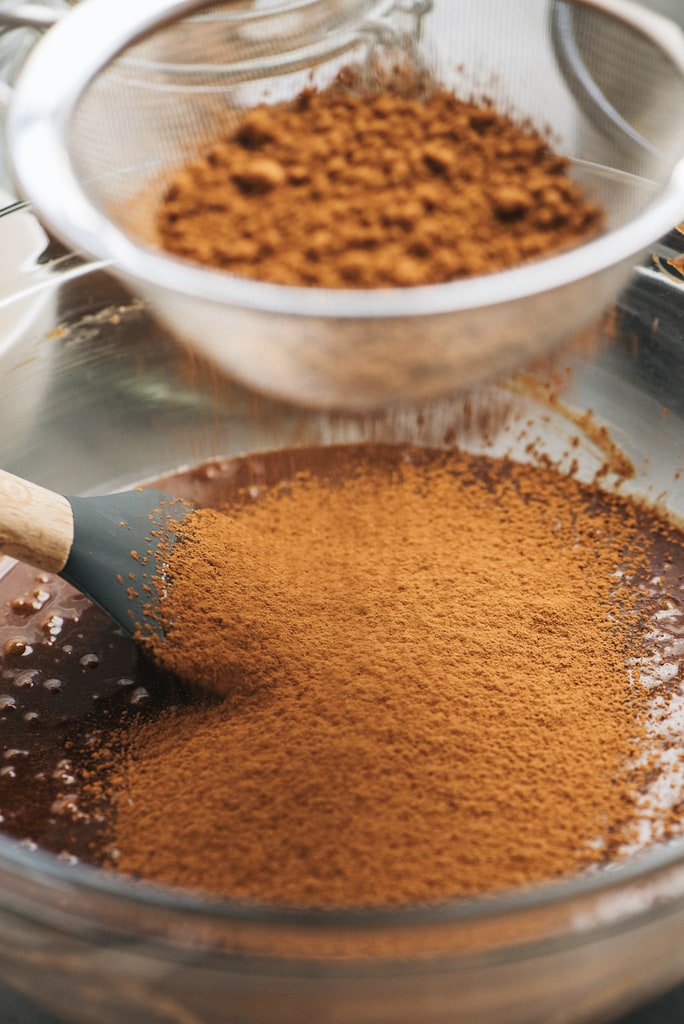 cocoa powder sifted into bowl of cake batter