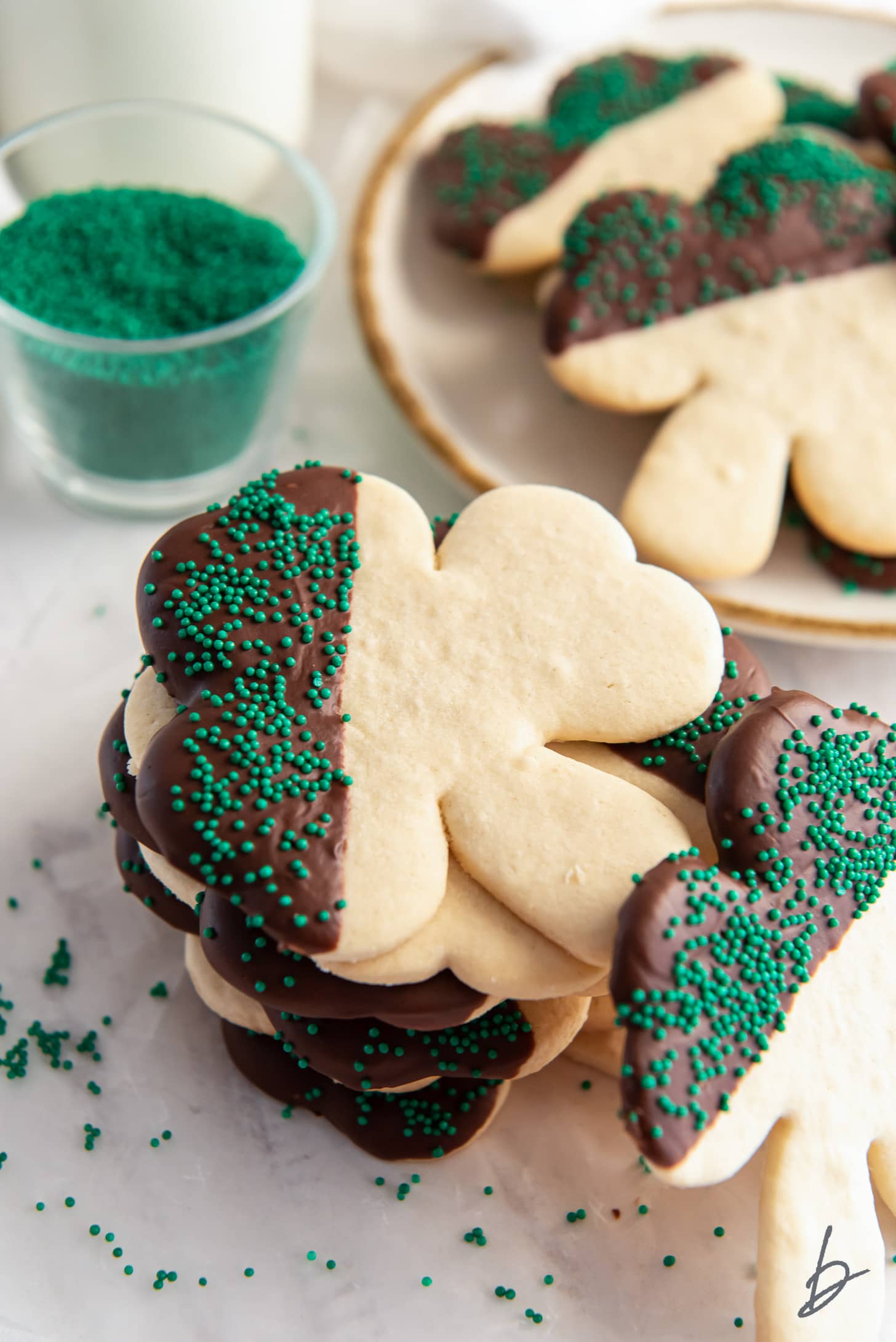 stack of chocolate dipped shamrock sugar cookies with green nonpareil sprinkles