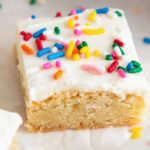 sugar cookie bar topped with buttercream frosting and rainbow sprinkles