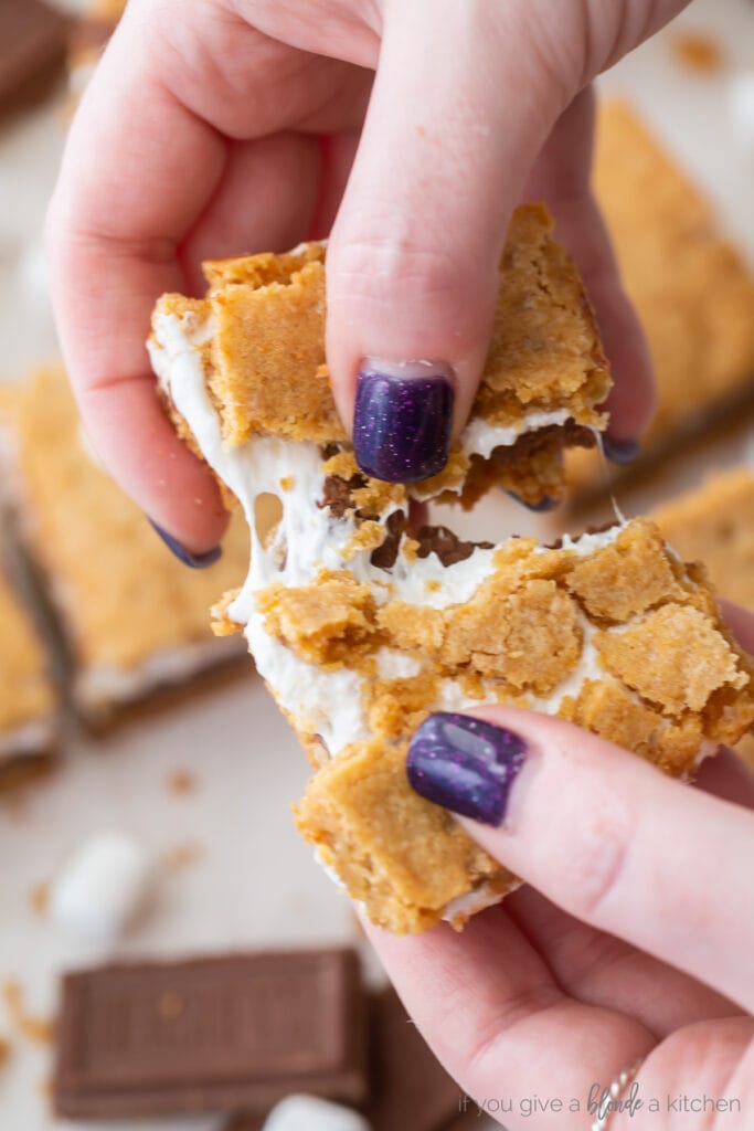 hands pulling apart smores bar to show marshmallow creme inside