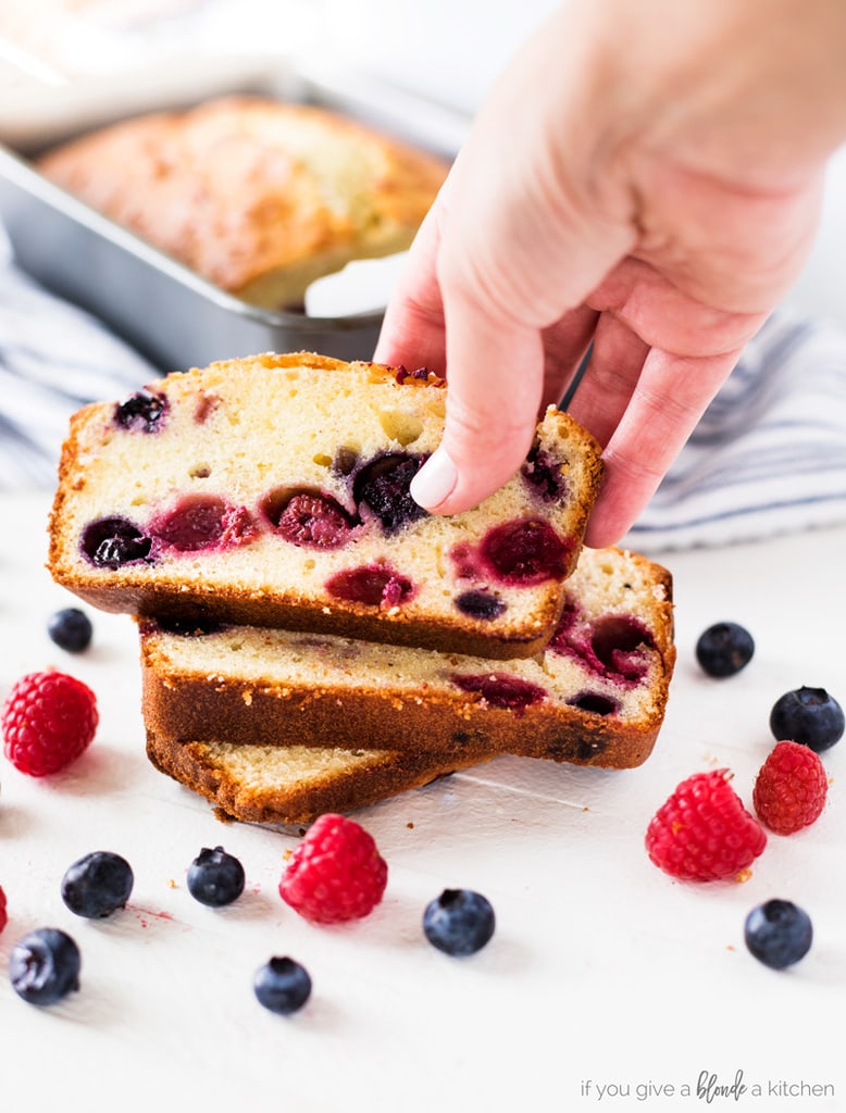 Blueberry raspberry pound cake hand reaching for slice with summer berries
