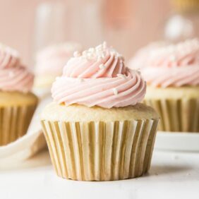 moscato cupcakes in gold paper liners topped with light pink frosting