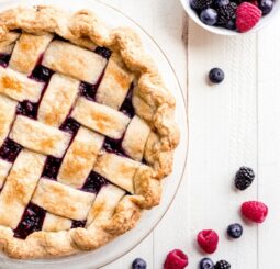 close of up lattice crust pie with berries next to it