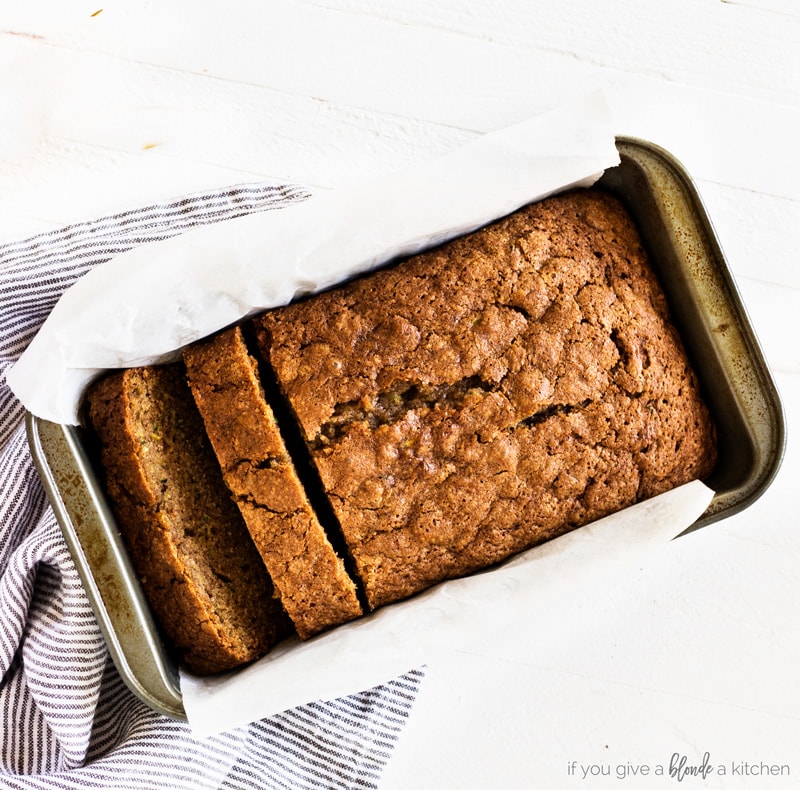 Moist zucchini bread in loaf pan with cloth and parchment paper