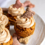 dog cupcake with frosting and biscuit garnish on a plate.