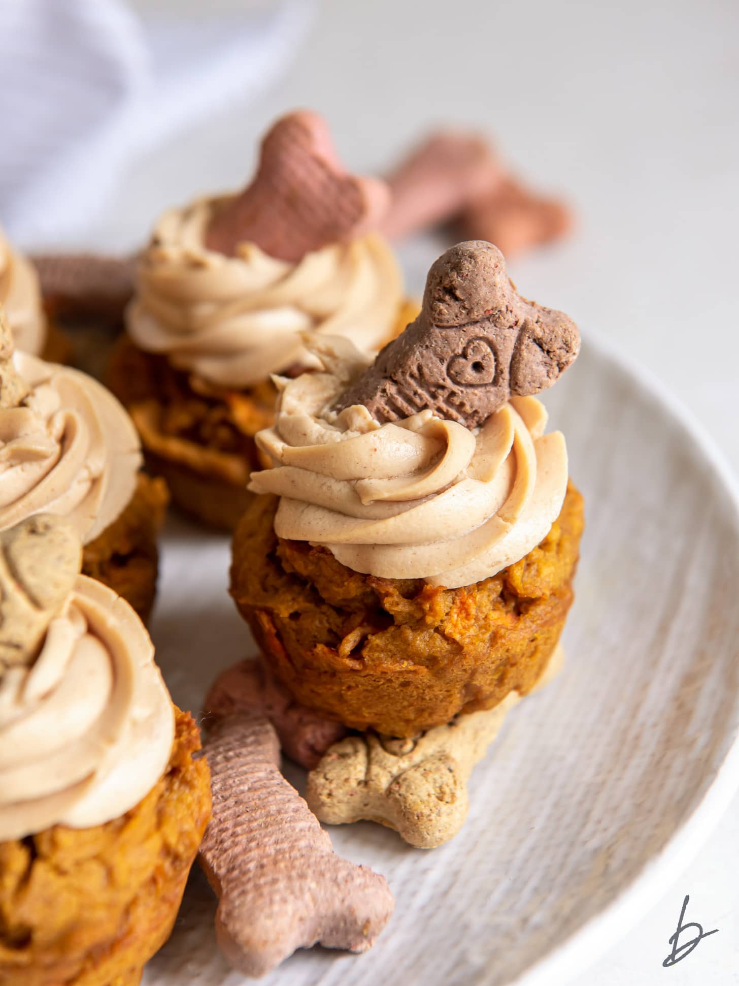 dog cupcake with frosting and biscuit garnish on a plate.