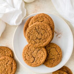 plate of ginger molasses cookies with a couple cookies next to plate with milk bottle