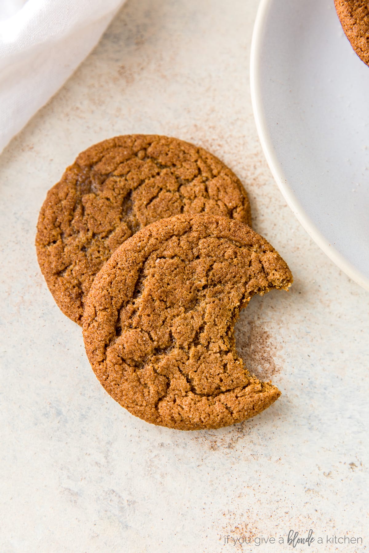 Chewy ginger molasses cookies with bite taken out of the cookie.