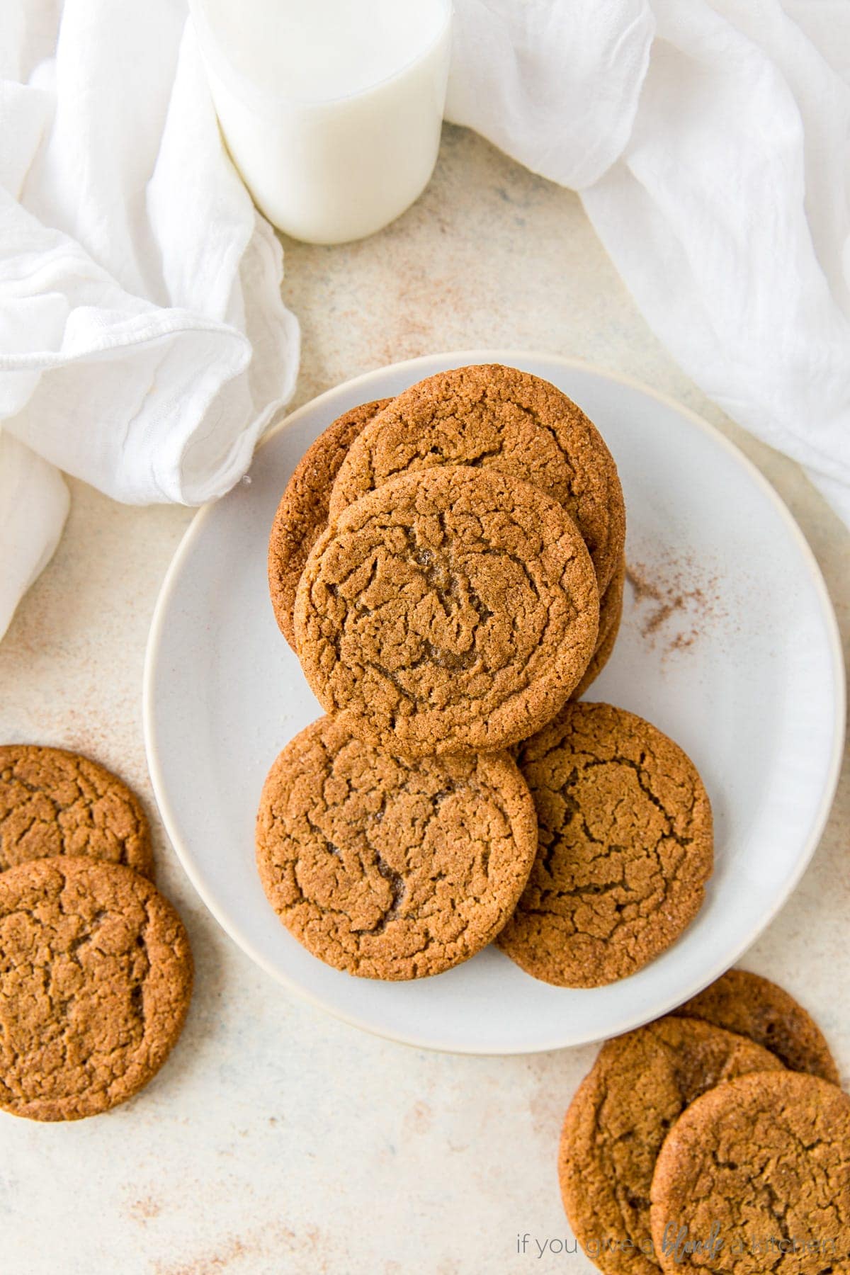 Chewy ginger molasses cookies on cooling rack with kitchen cloth.