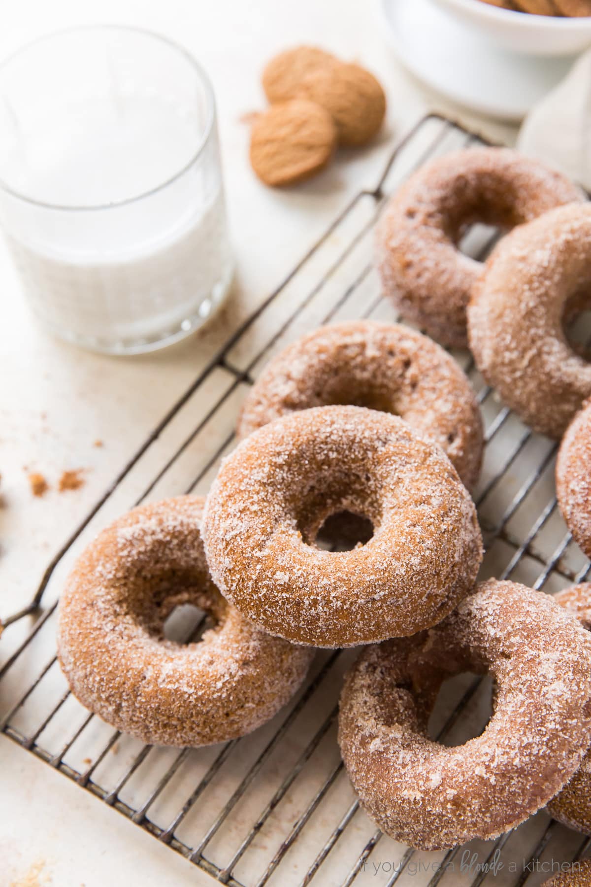 Gingerbread donuts with cinnamon sugar on wire cooling rack next to glass of milk