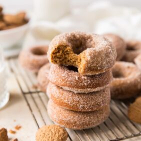 Stack of four gingerbread donuts on wire rack; top donut with a bite taken out