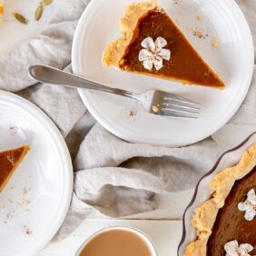 slices of pumpkin pie on round white plates with forks