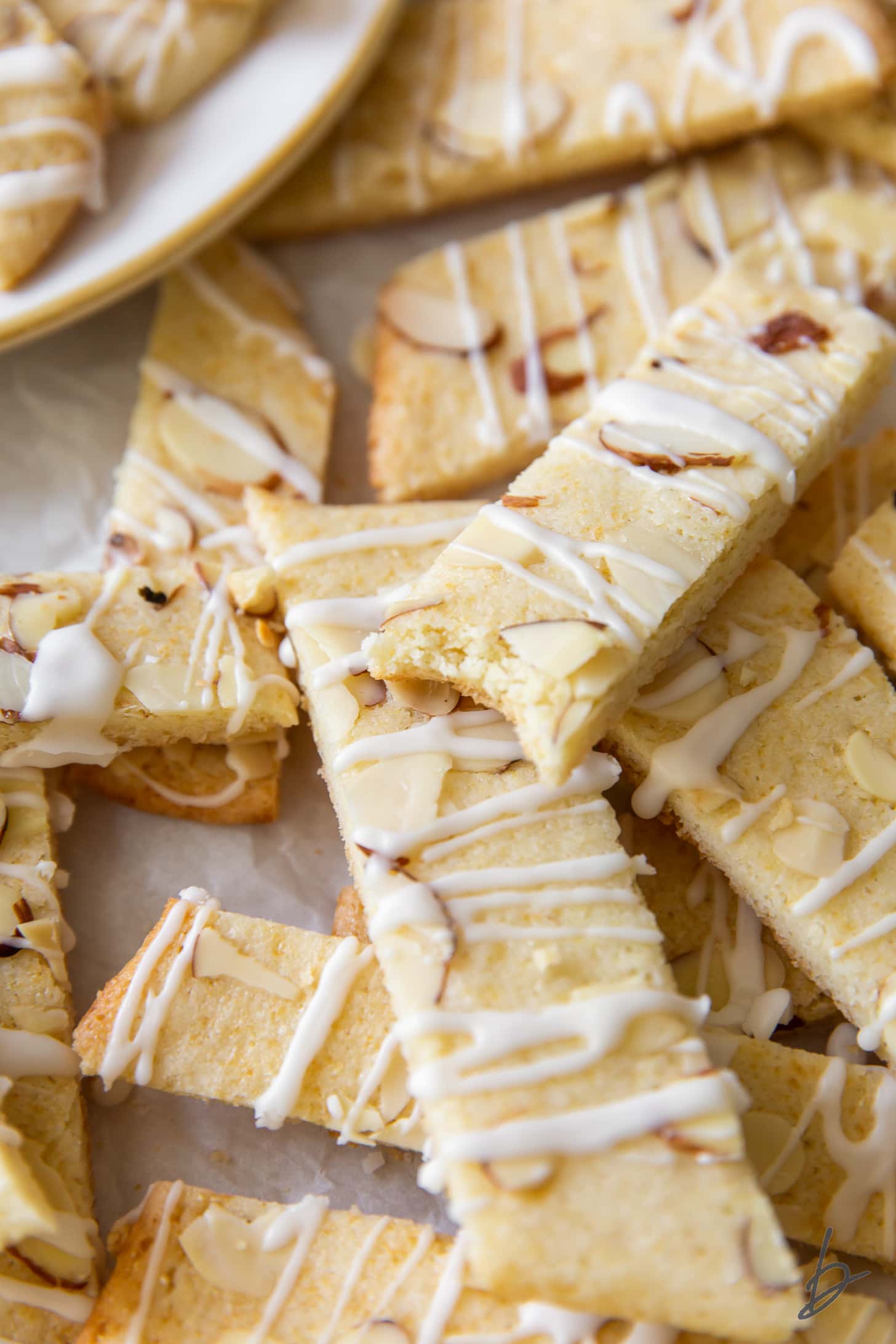 pile of scandinavian almond bars with icing and slivered almonds with top bar missing a bite.