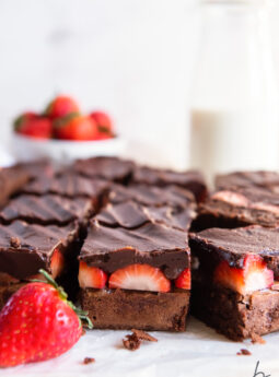 side of cut chocolate covered brownies showing layers of brownie, strawberries and chocolate ganache