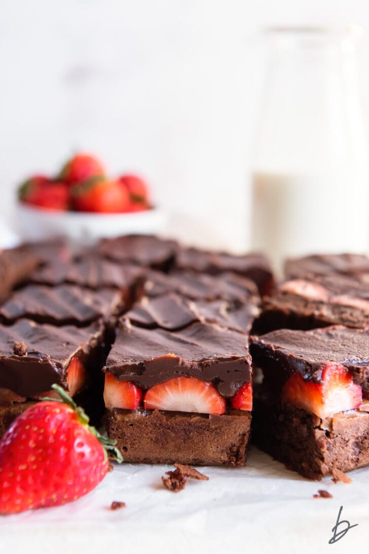 side of cut chocolate covered brownies showing layers of brownie, strawberries and chocolate ganache