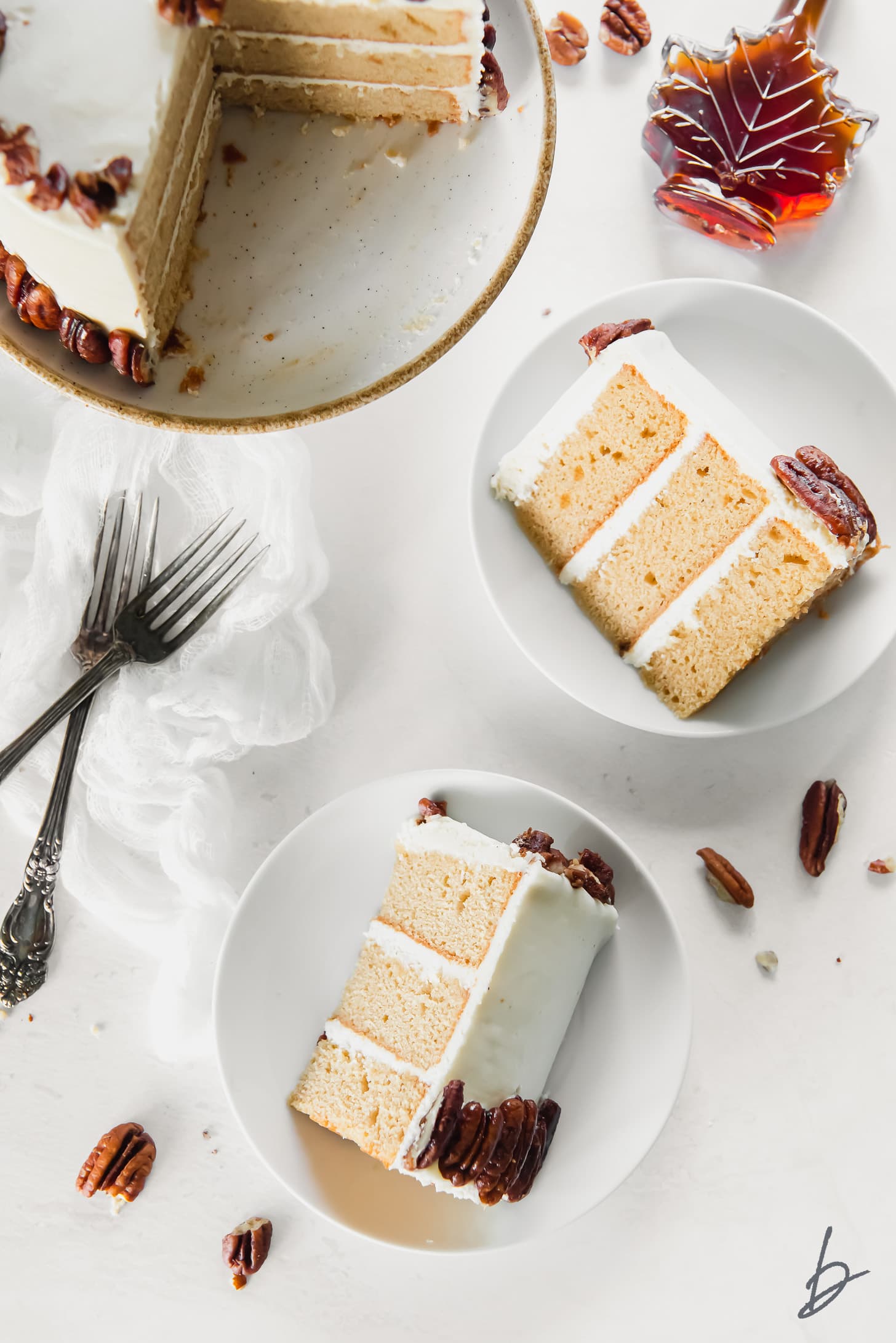 two white round plate with slices of layered maple cake and candied pecans