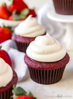 red velvet cupcake with cream cheese frosting near fresh strawberries