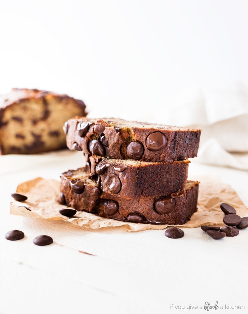 Chocolate chip banana bread recipe slice with chocolate chips on parchment paper, white background