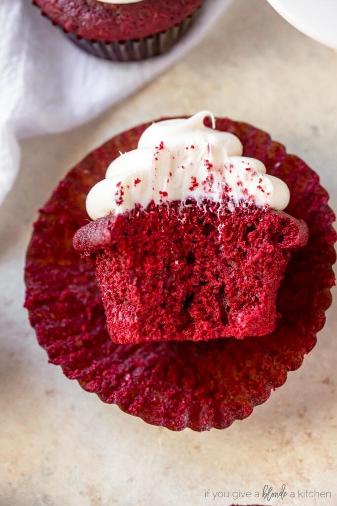 red velvet cupcake with a bite on open paper cupcake liner