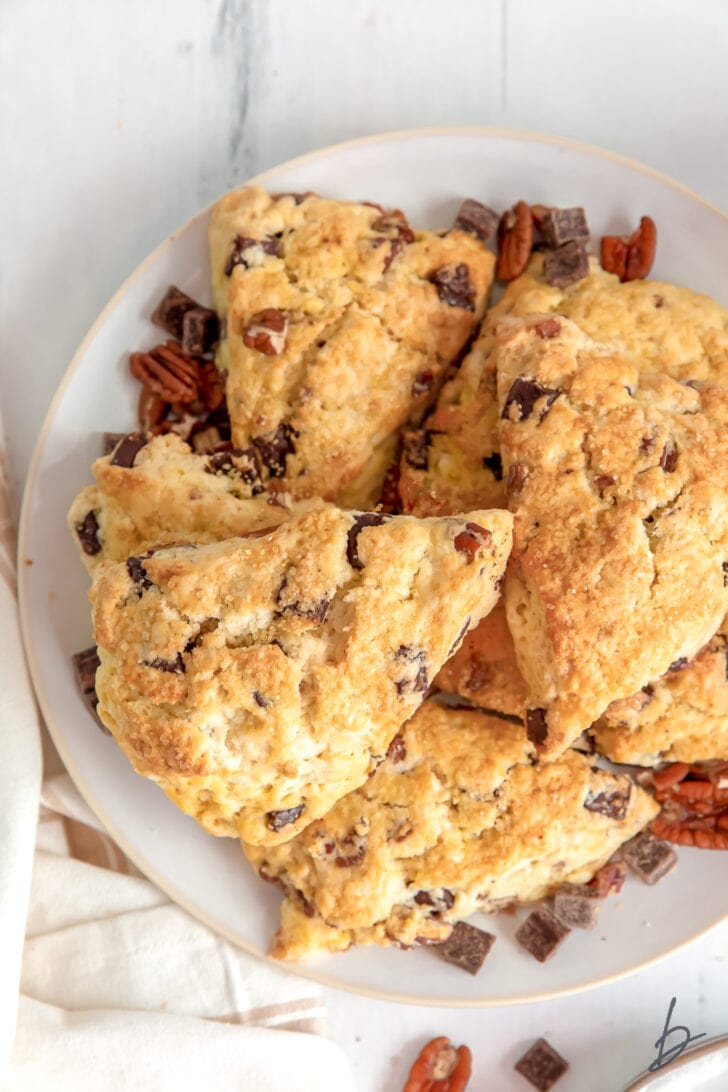 Ina Garten's chocolate pecan scones recipe with scones on plate with chocolate chunks and pecans