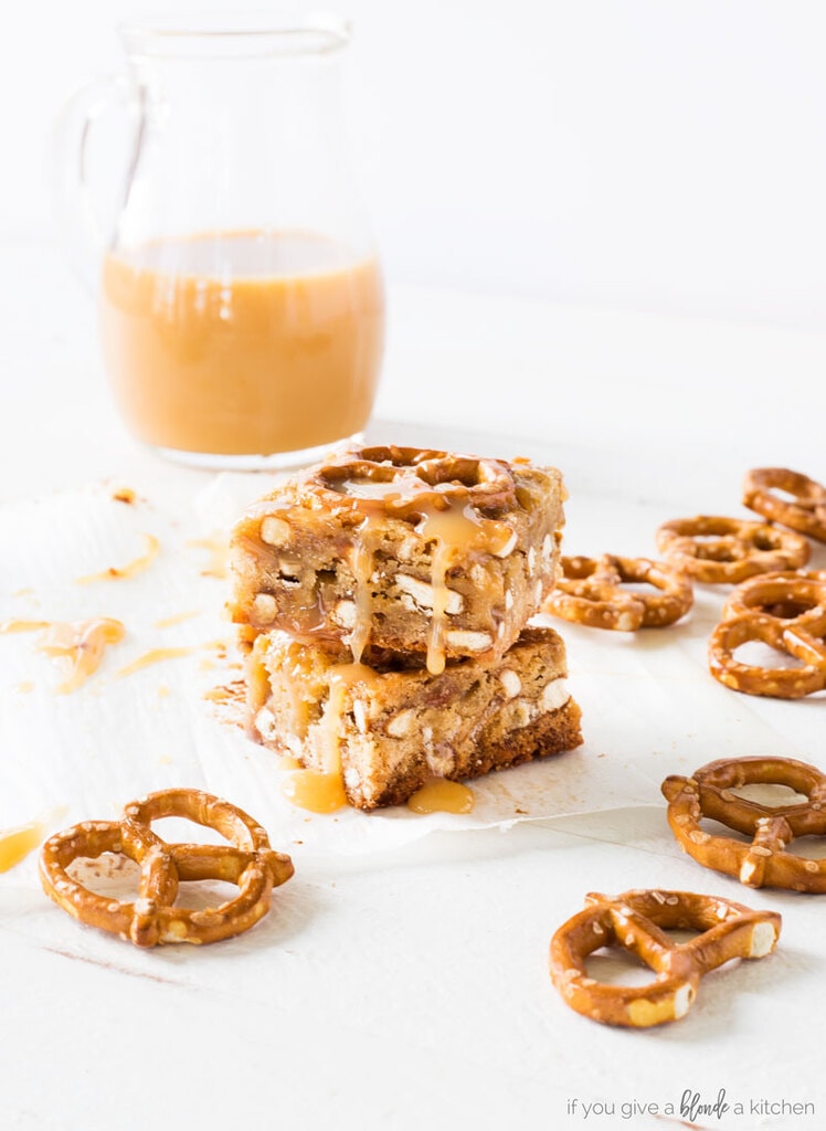 two caramel pretzel blondies stacked on top of each other. pretzel twists next to blondies