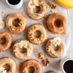 banana donuts with brown butter glaze and banana slices and chopped walnut as garnish.