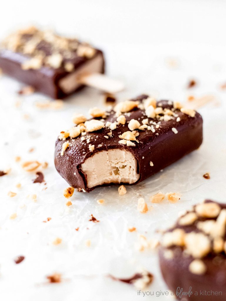 yogurt peanut butter popsicles with bite and chopped peanuts