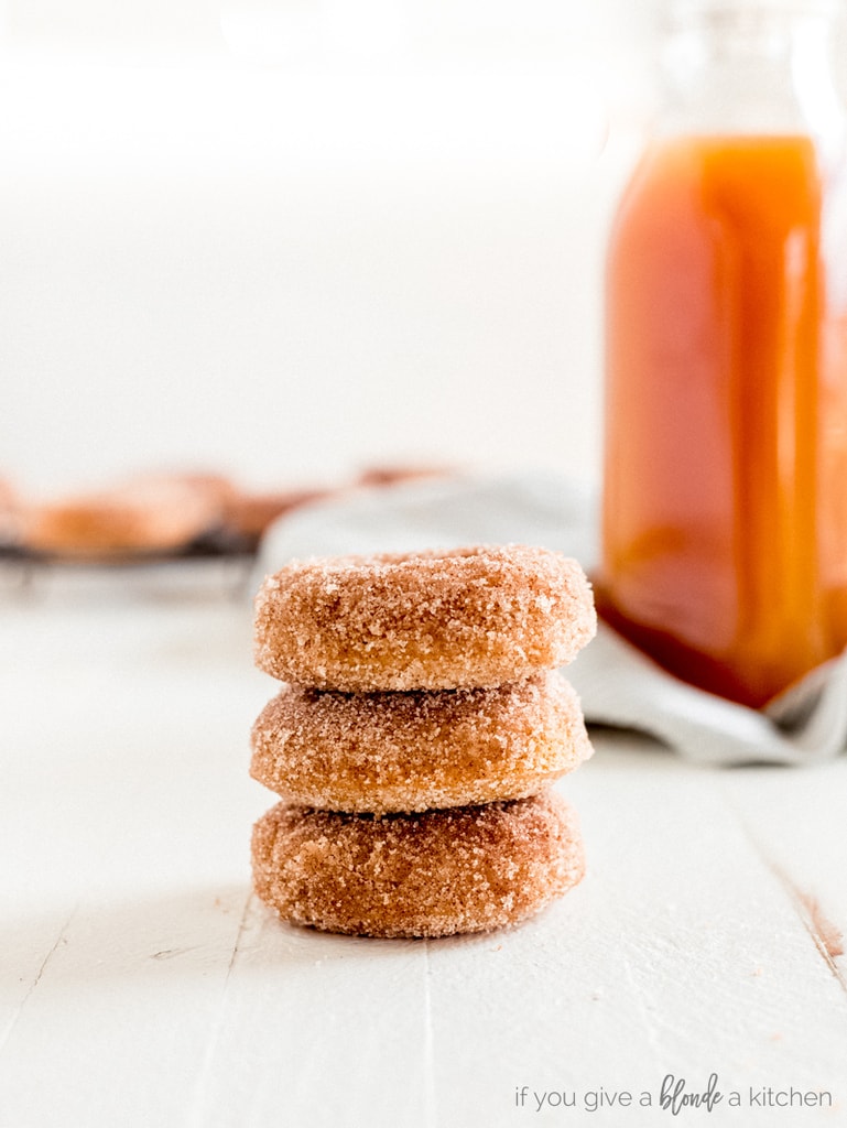 stack of three apple cider donuts with cider jug