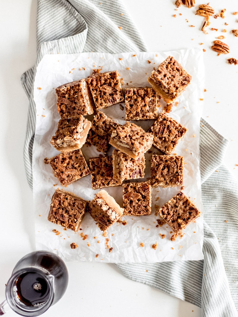 maple pecan pie bars cut into squares on parchment paper with pure maple syrup 