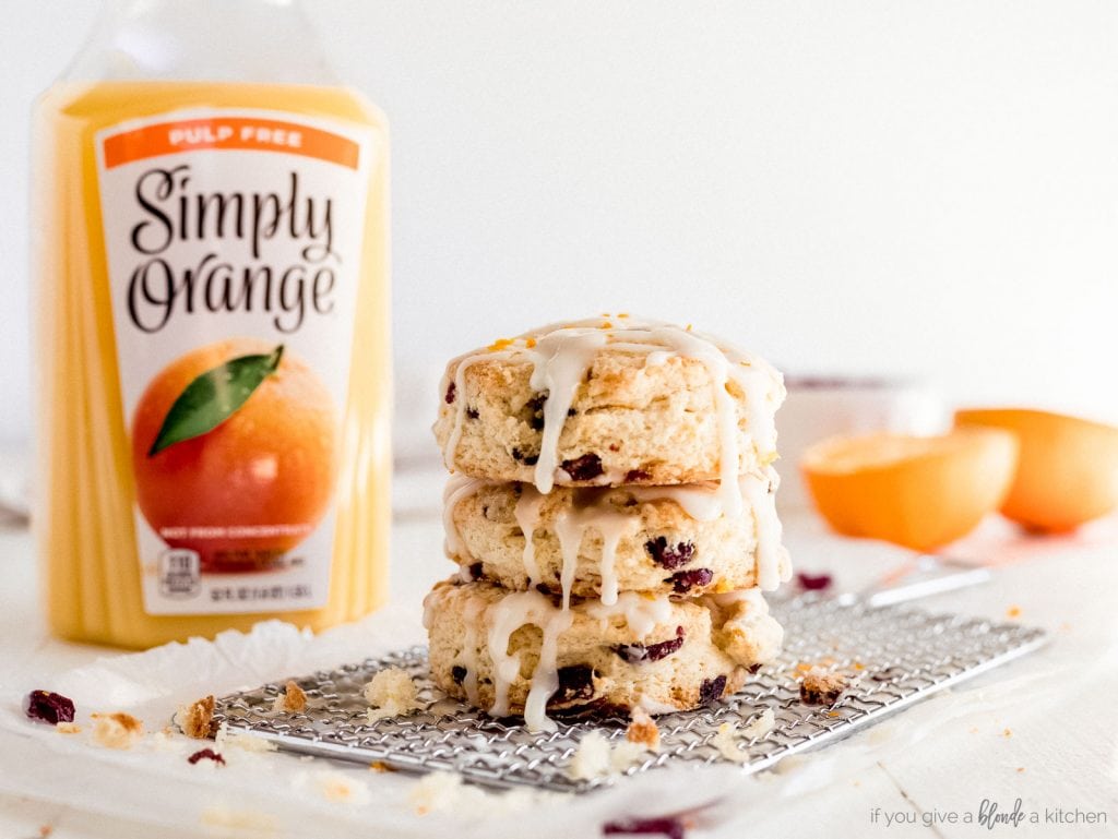 stack of cranberry orange scones with bottle of orange juice