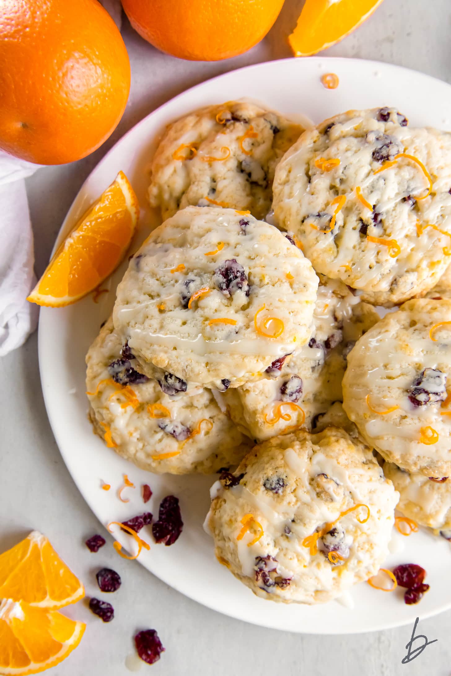 glazed cranberry orange scones on a plate with orange zest.