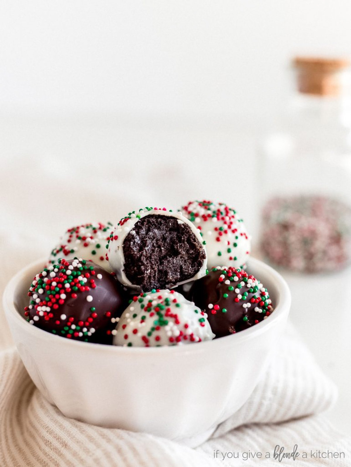 white chocolate oreo truffles and dark chocolate oreo truffles with christmas sprinkles in white bowl.
