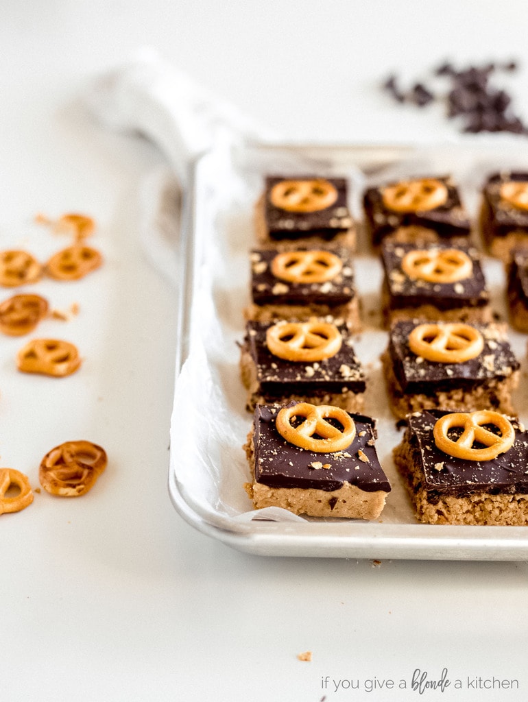 peanut butter pretzel bars on wax paper on baking sheet