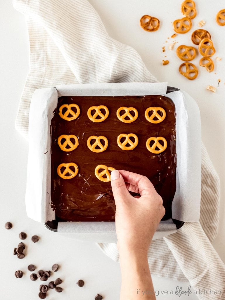 step by step mini pretzels being placed on top of melted chocolate layer