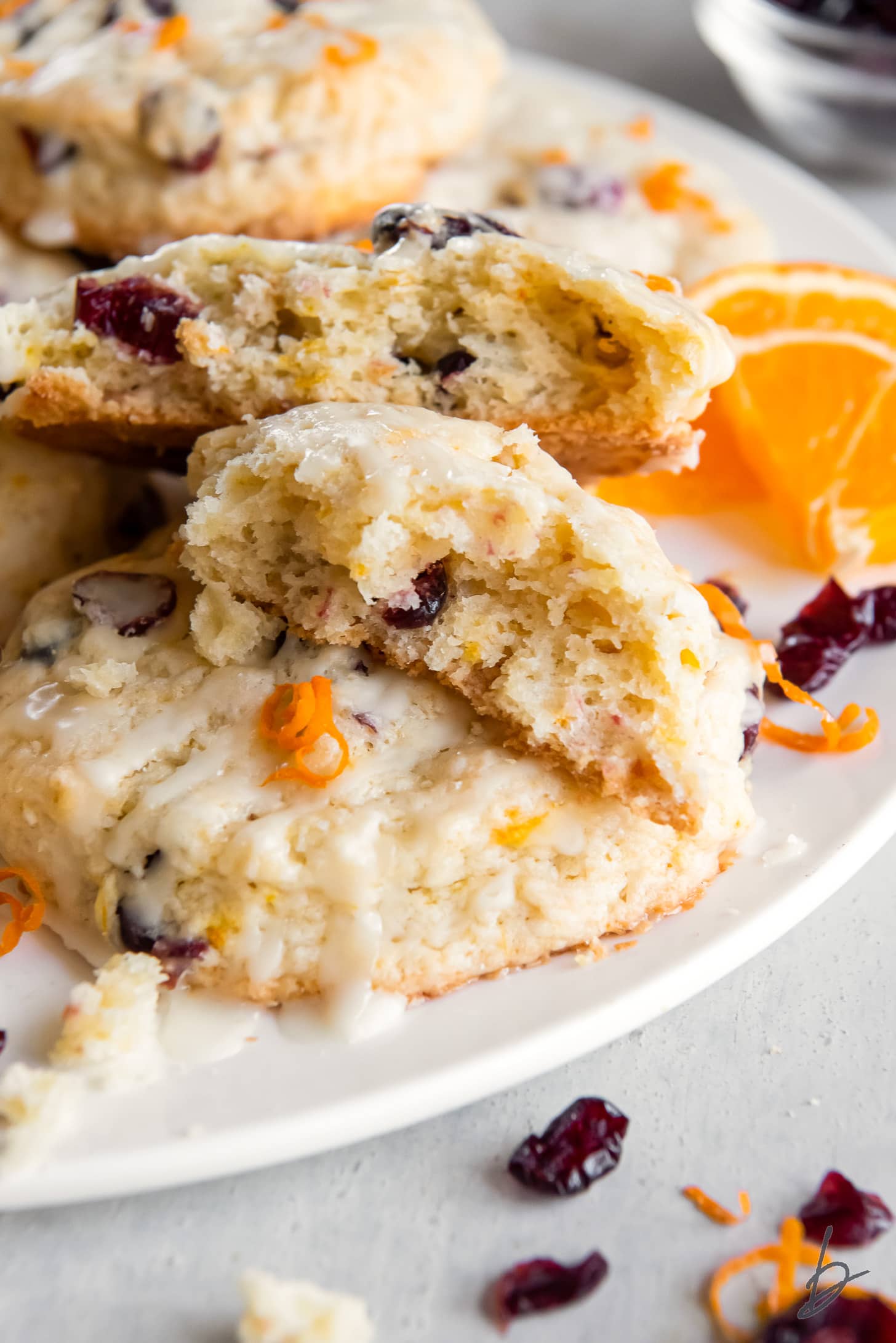 two halves of a cranberry orange scone on top of more scones on a plate.