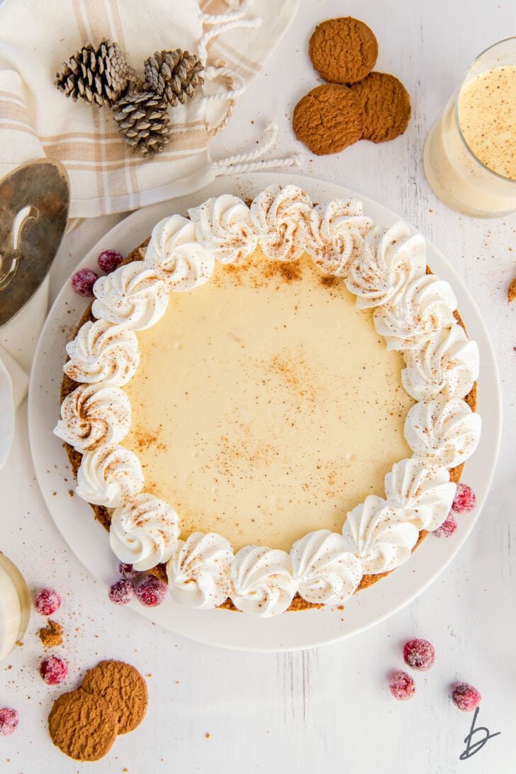 eggnog cheesecake garnished with whipped cream, dusting of nutmeg and sugared cranberries