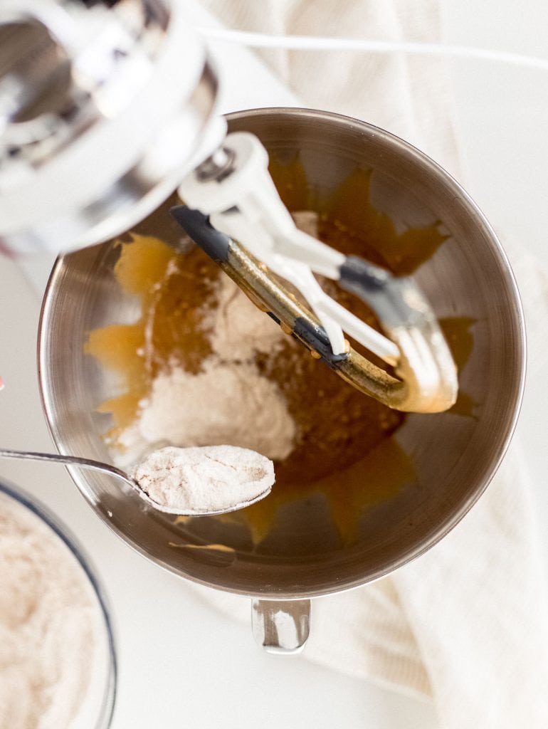 spoon adding flour to bowl of stand mixer