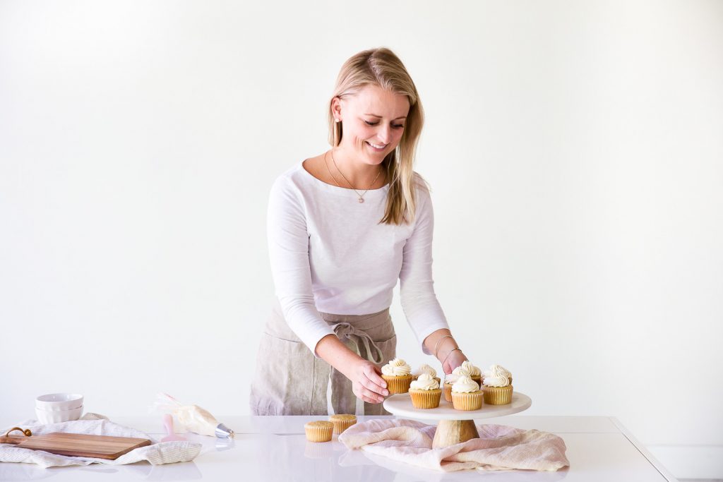 haley baker placing vanilla cupcakes on marble cake stand