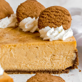 side of pumpkin cheesecake slice with gingersnap crust. Slice garnished with whipped cream and gingersnap cookie