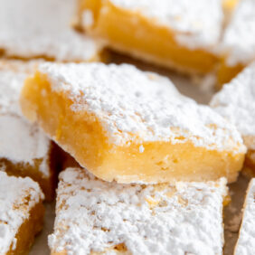 lemon bar propped on its side on top of more lemon bars with confectioners' sugar on top