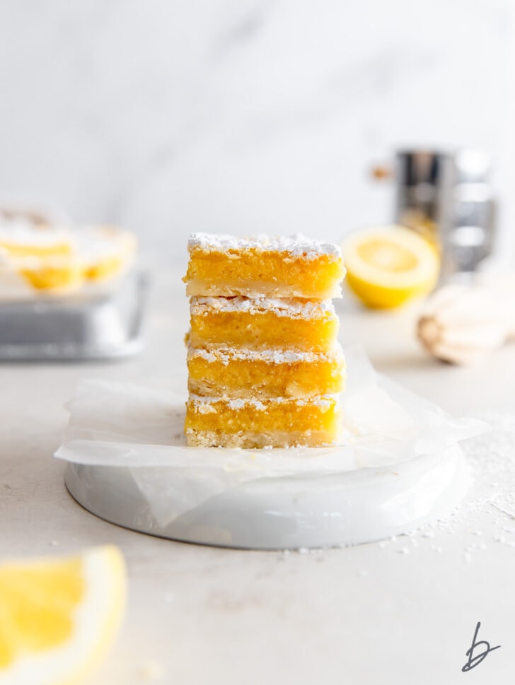 stack of four lemon bars with powdered sugar and gooey filling