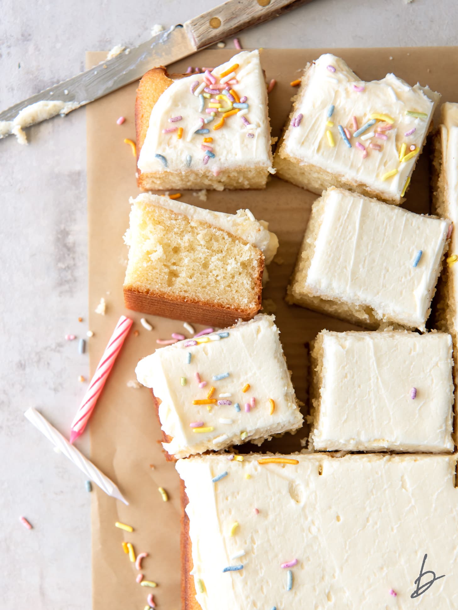 vanilla buttercream frosting on top of vanilla sheet cake cut into squares.