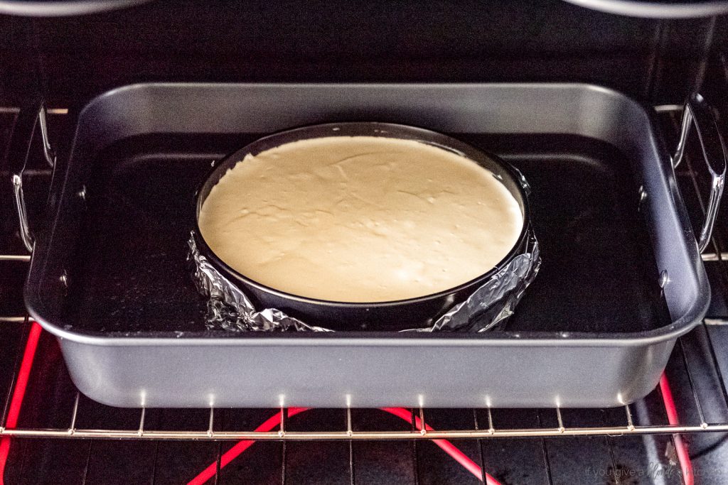cheesecake in water bath in roasting pan in oven
